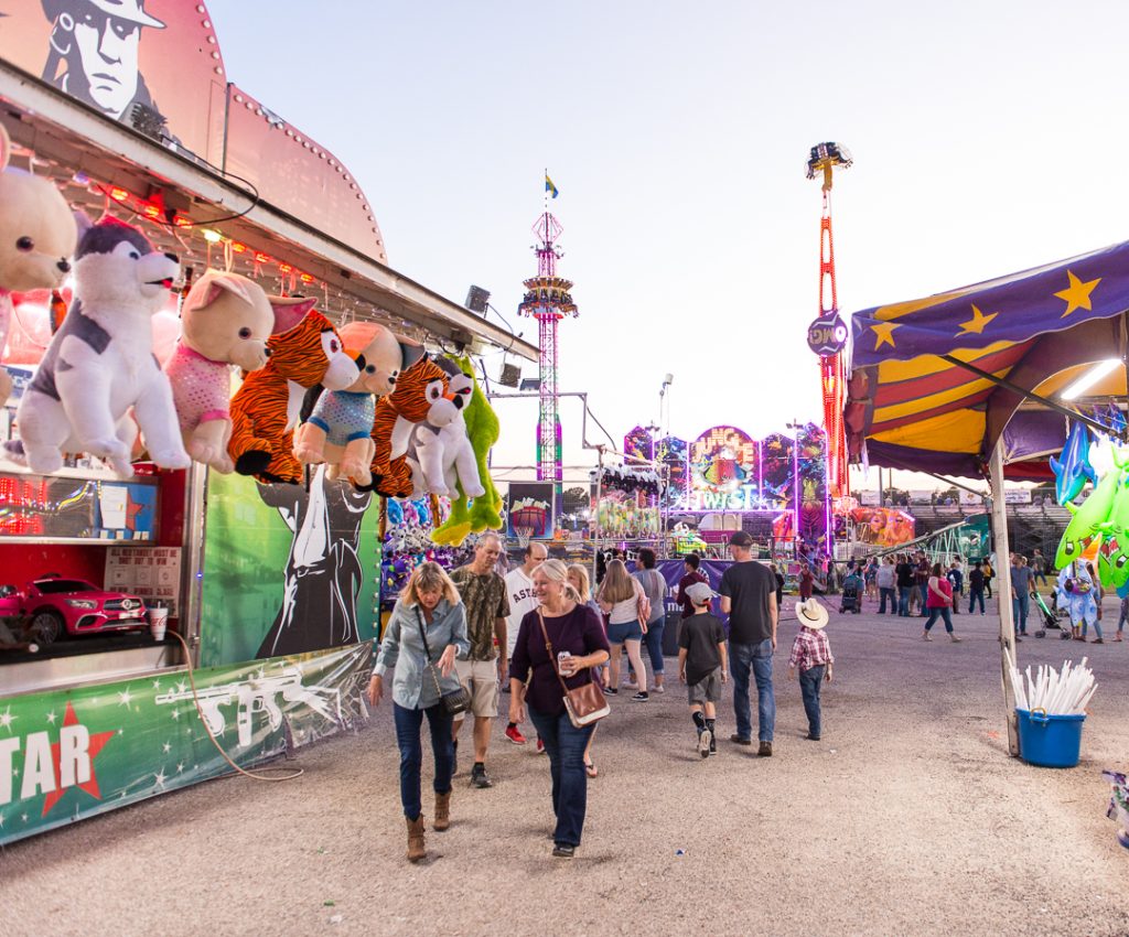 A group of people walking through the fair games at the Washington County Fair.