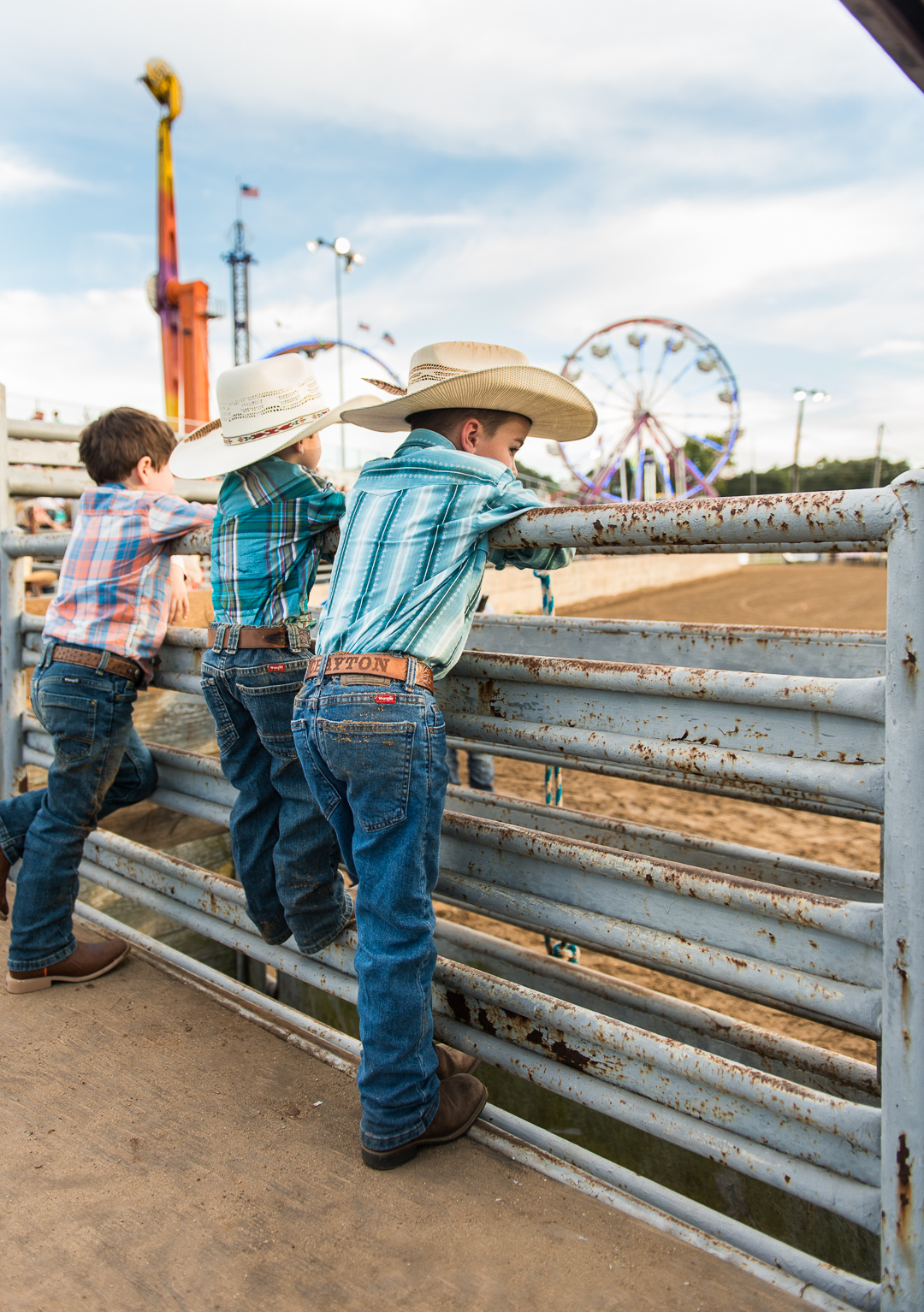 young boys in cowboy hats watching the rodeo