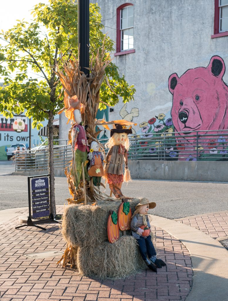 Scarecrows on hay bales as fall decorations in Downtown Brenham.