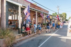 Groups of people walking along the sidewalk in downtown Chappell hill.