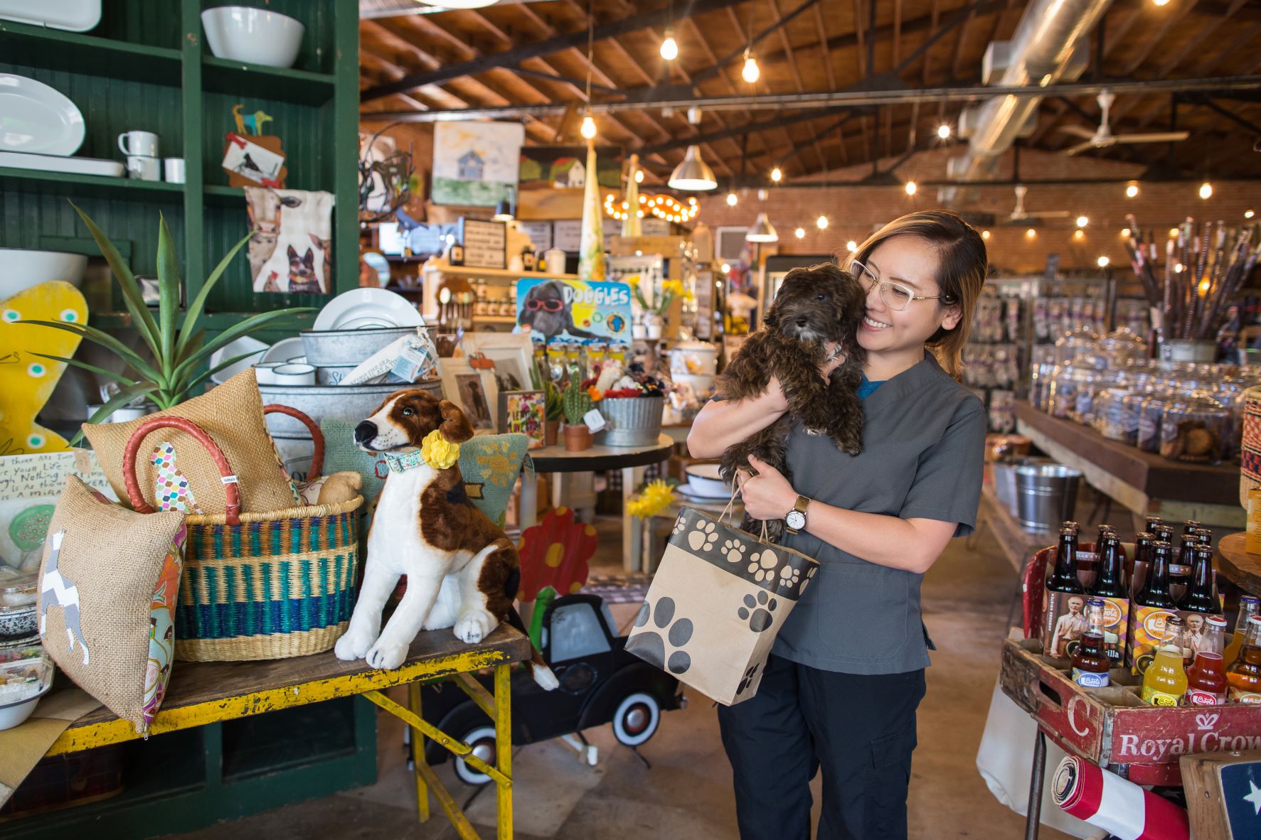 Woman holding dog and shopping bag inside of Puppy Dawgs & Cat Tails