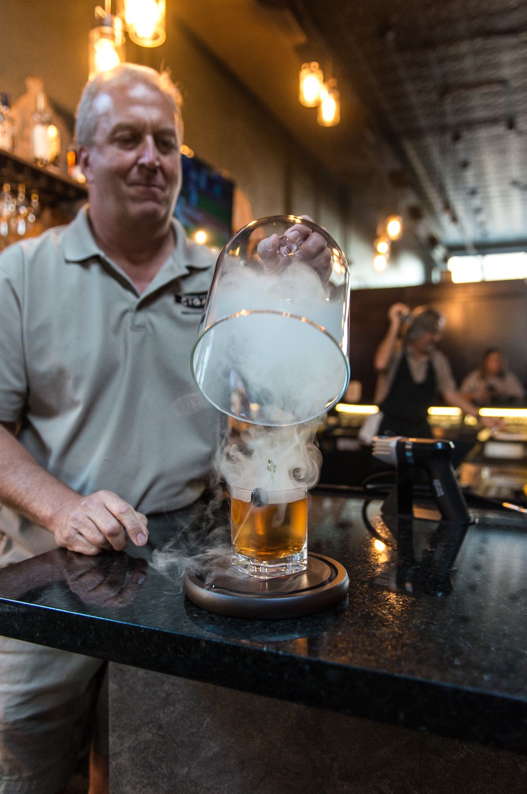 Man making smoked old fashioned with smoke coming out at Brown Water Cigar Bar. - Photo by Natalie Lacy Lange
