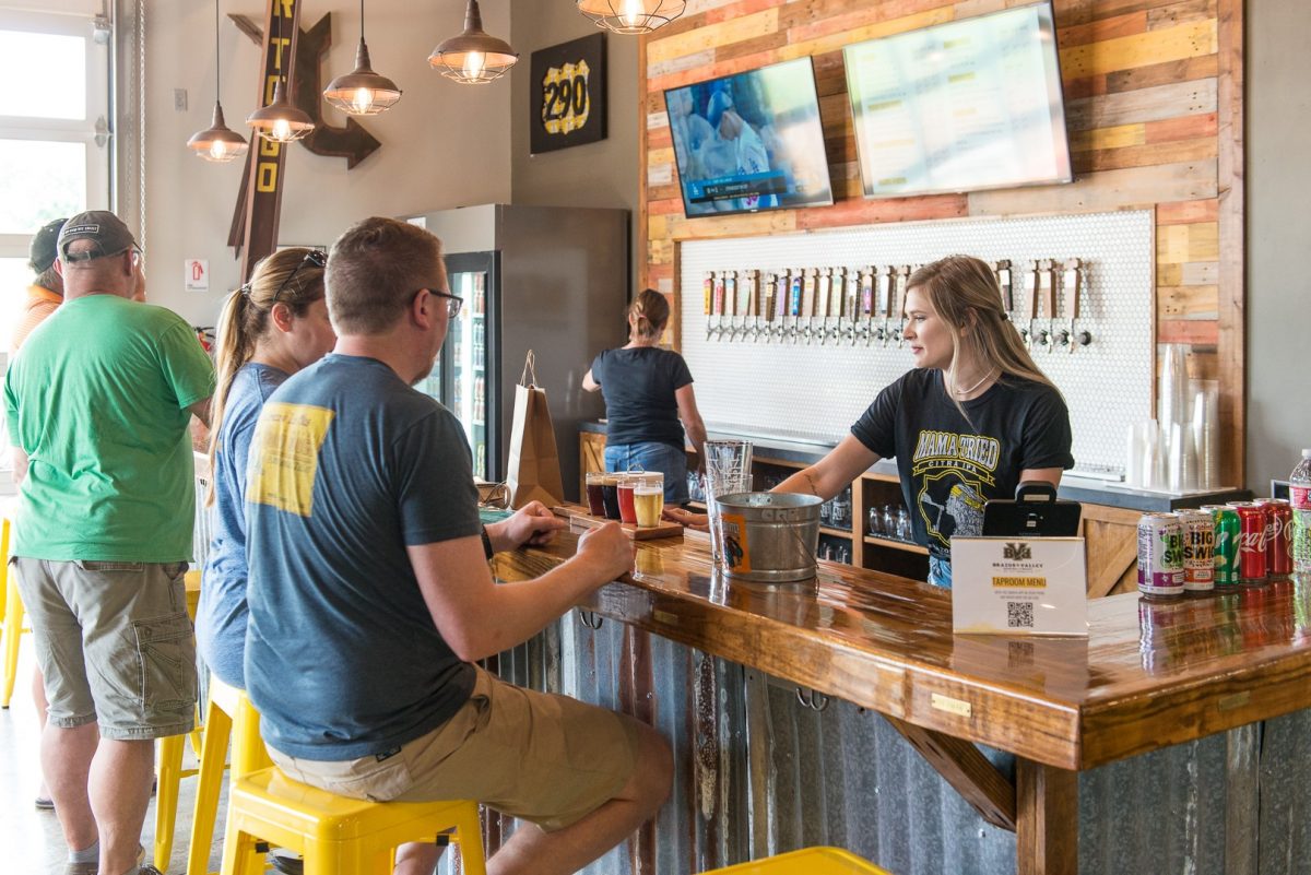 people sitting at a bar being served a flight. Brazos Valley Brewery