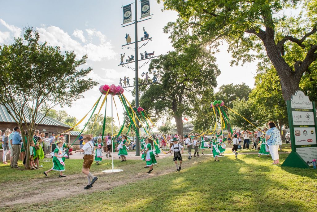 Children in traditional Bavarian clothing dancing around the Maypole in Fireman's Park at Maifest