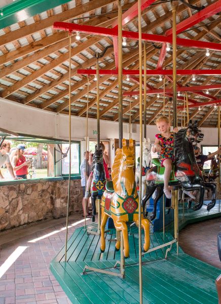 a child riding a wooden carousel horse on the antique carousel in Fireman's Park, Brenham, Texas