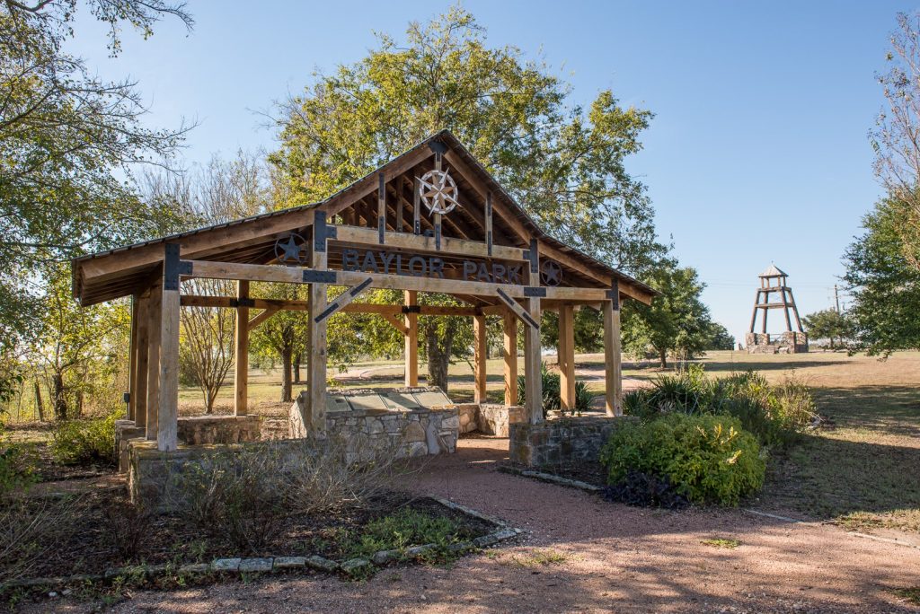 An entrance to Old Baylor Park. A wooden structure with signage underneath.