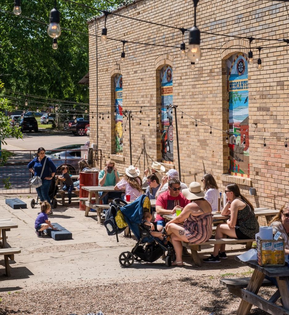 groups of families with young children at picnic tables on the patio at Pioneer Smokehouse and Mercantile