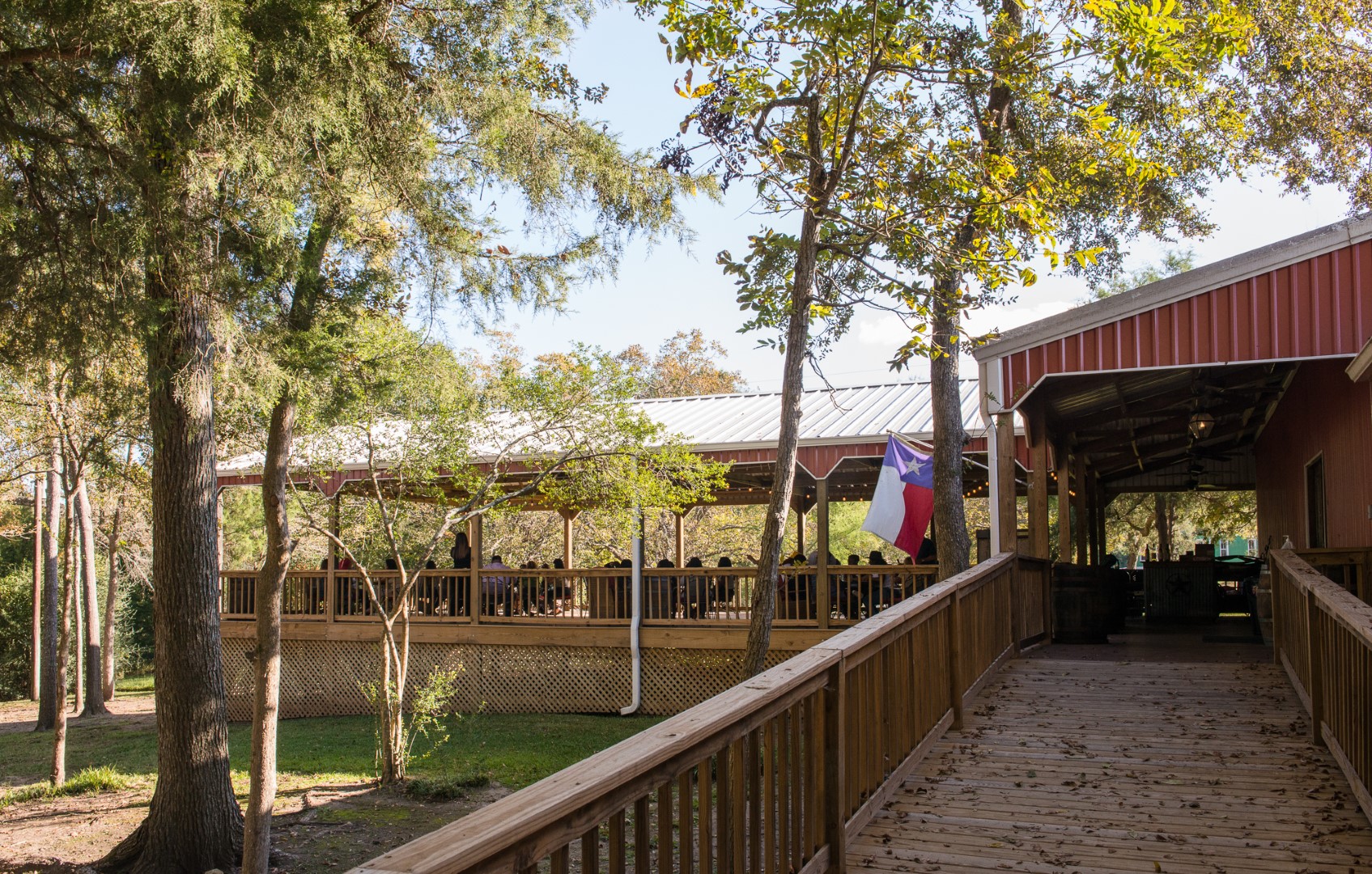 large group of people sitting at tables on a large covered porch.