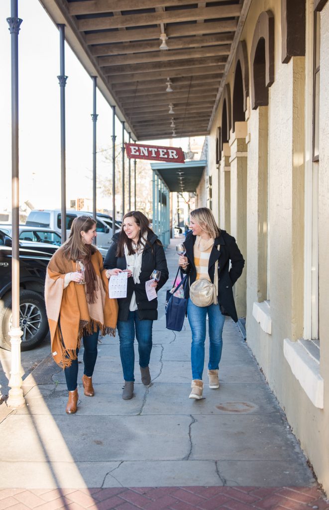 Three women walking and smiling on the sidewalk in Downtown Brenham.