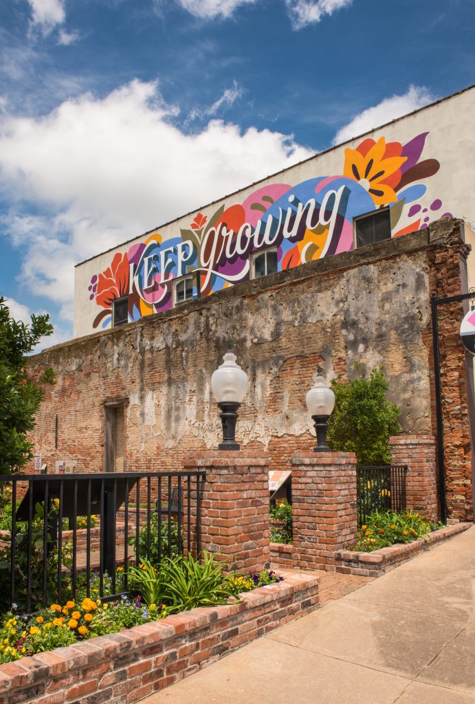 Exterior of a historic building with mural of "keep growing" on the side of it.