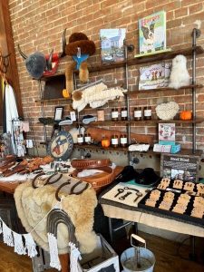 The inside of Chupacabra Leather Co. There is a table filled with handmade leather goods.