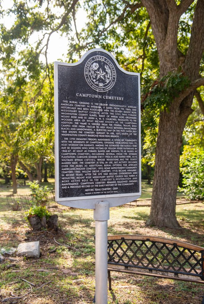 A historical markers guide at Camptown Cemetery. In the back there is a large tree.