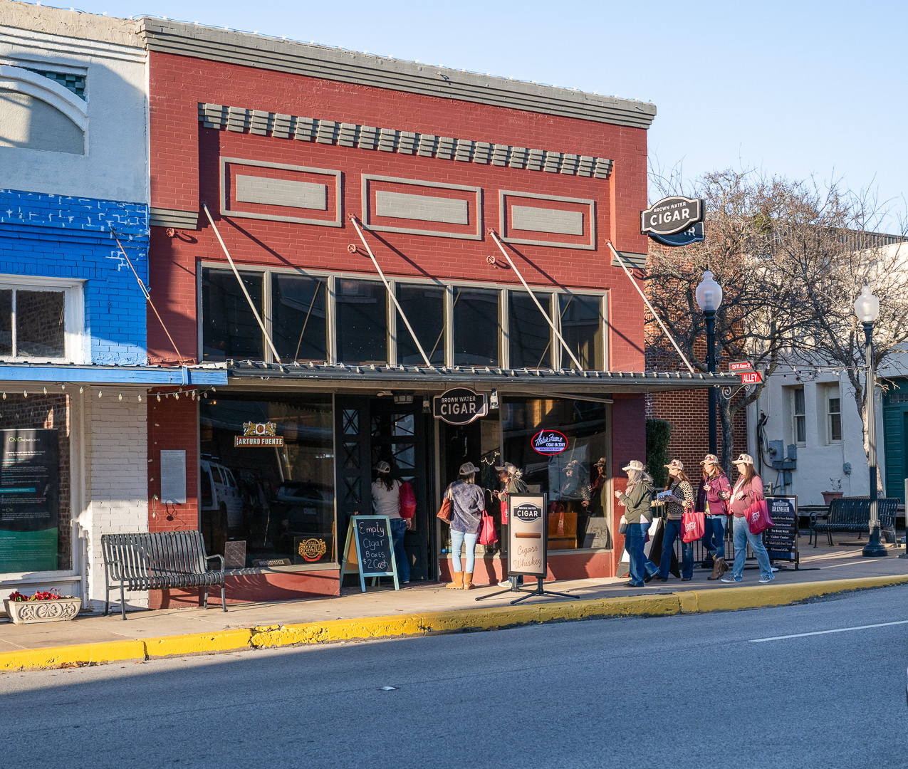Uptown Swirl participants head inside of Brown Water Cigar Bar for a wine tasting on a sunny day in Downtown Brenham.
