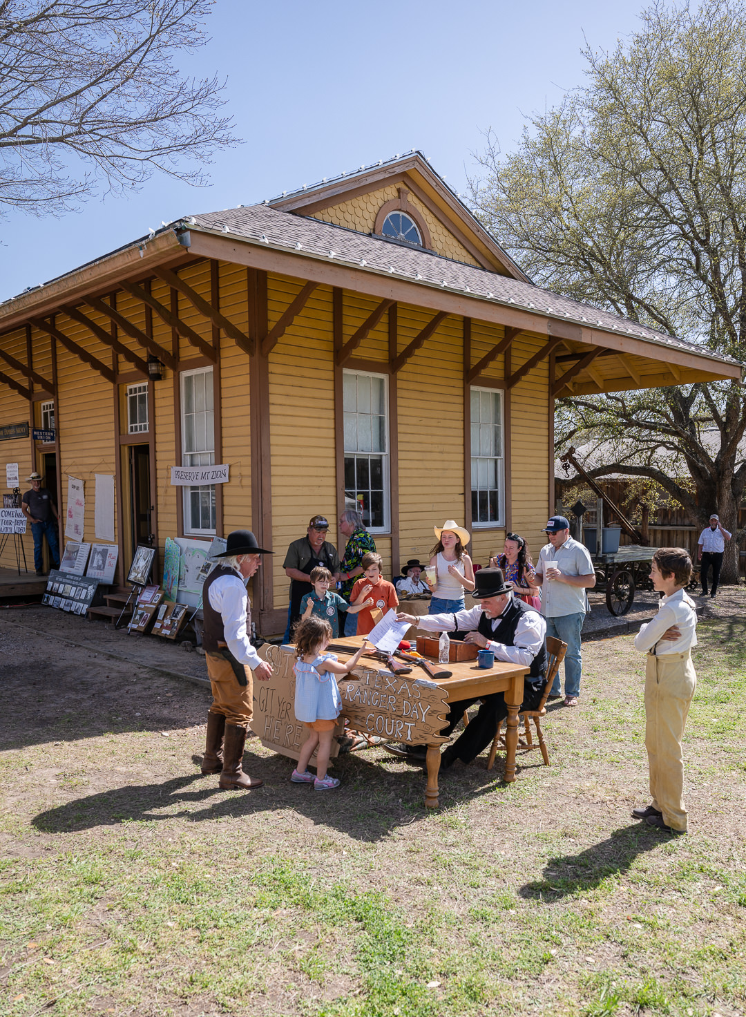 Kids explore period displays in front of a historic train depot in Burton, Texas.