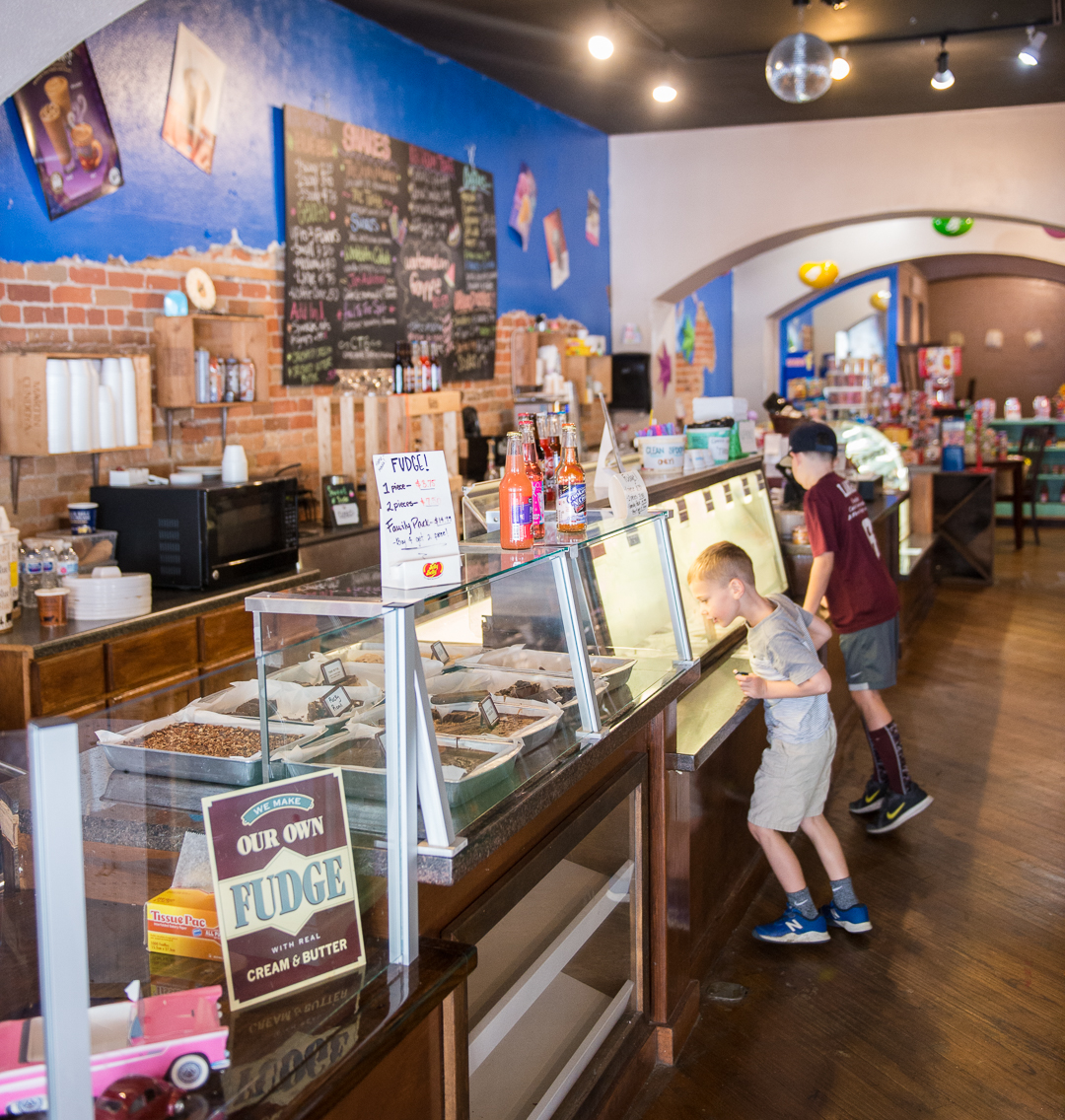 kids look at a selection of ice cream and confections in the cabinet at Yumm Sweets & Eats