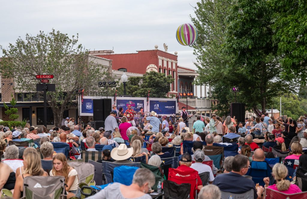 A crowd listens to live music at Hot Nights Cool Tunes in Downtown Brenham, Texas.
