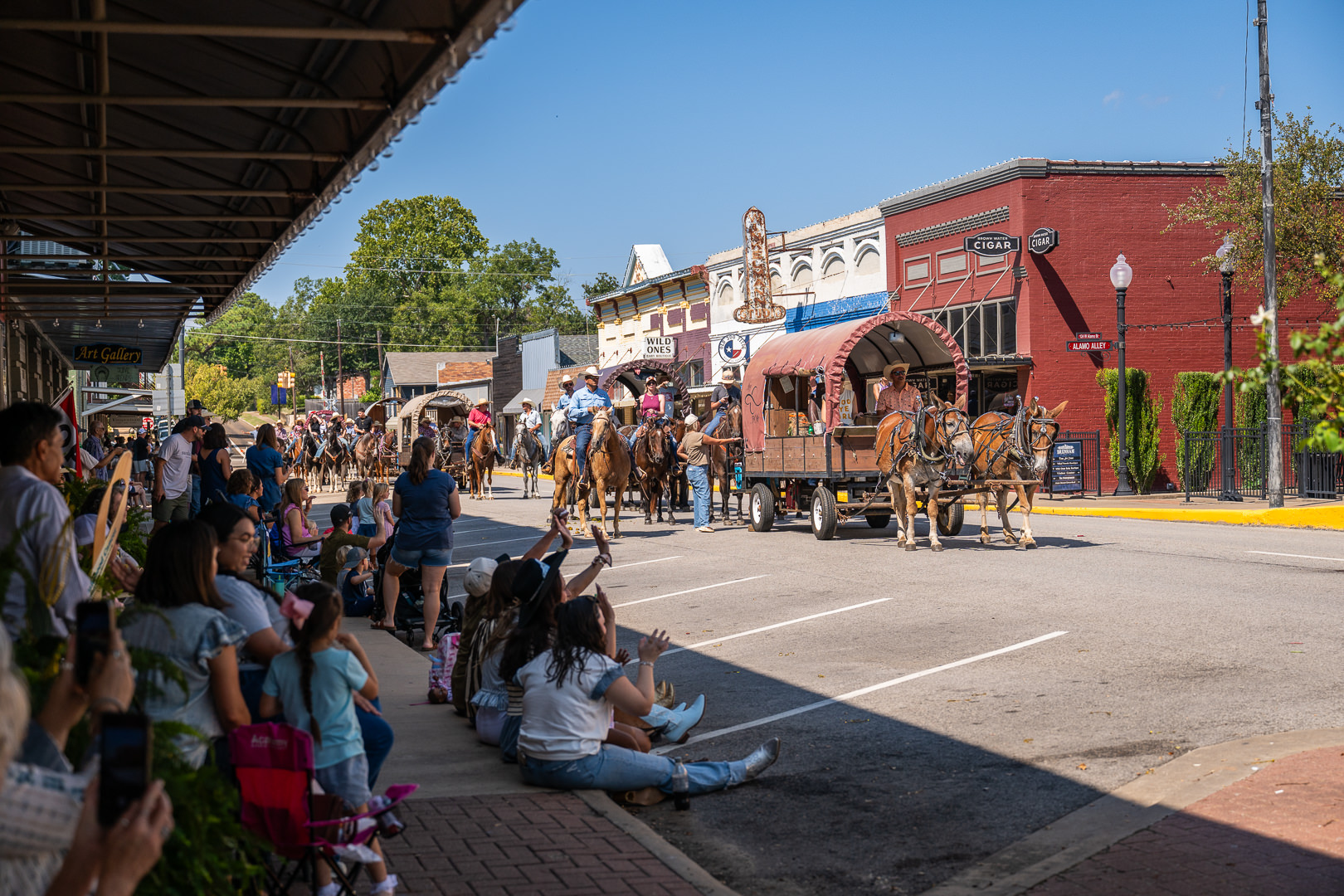 Crowds watch as horses-drawn wagons and riders on horses parade down Alamo street during the opening parade for the Washington County Fair in historic Downtown Brenham.